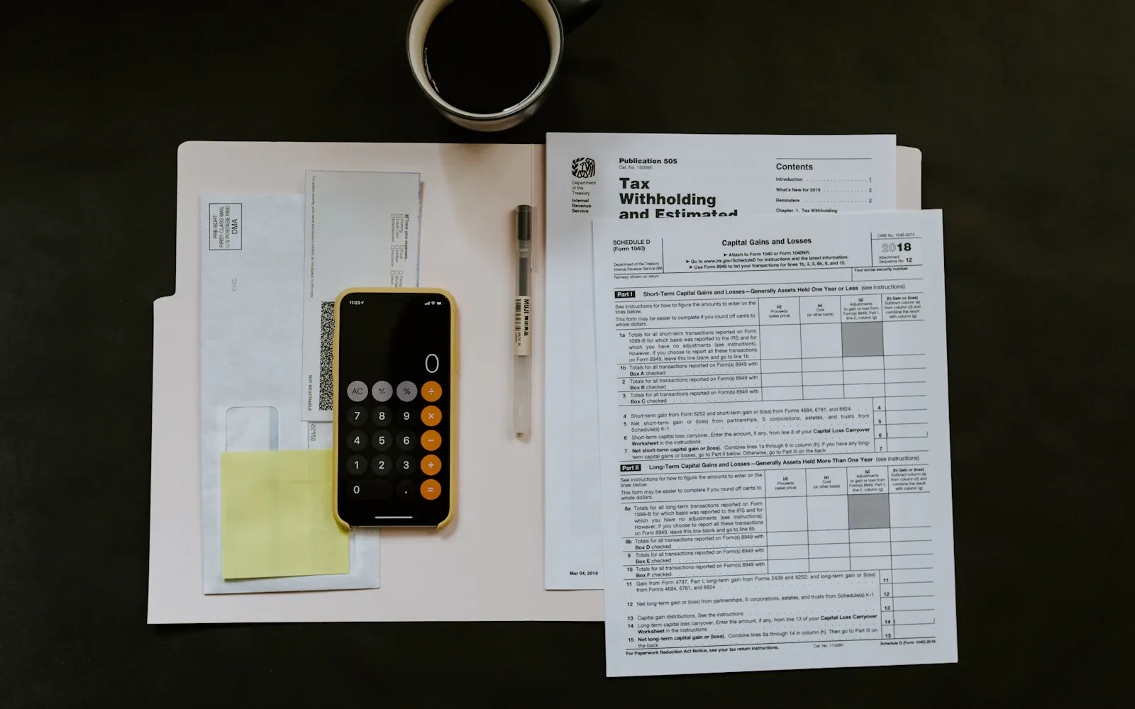 Mobiltelefon, kuglepen og skattepapirer på en hvid mappe